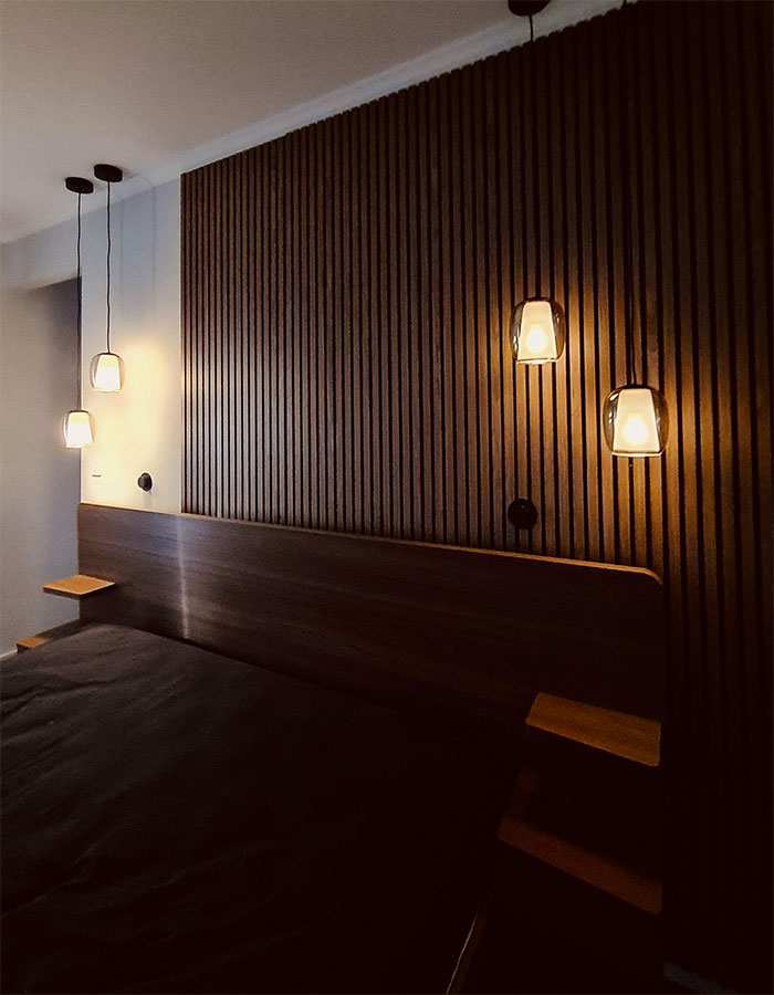Bedside pendant lights and switches installed on timber feature wall